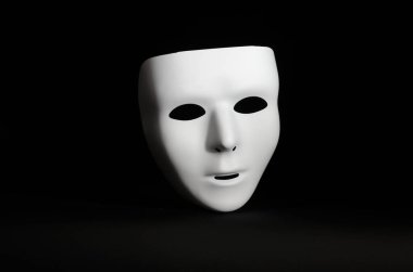 boş, duygusuz bir maskeli maske yalın siyah bir arka plan karşı vurgulanır 