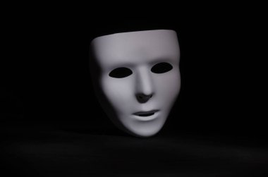 boş, duygusuz bir maskeli maske yalın siyah bir arka plan karşı vurgulanır 