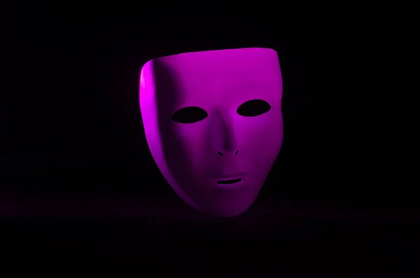 一个空白的 没有感情的伪装面具在紫红色在赤裸裸的黑色背景下突出显示 — 图库照片