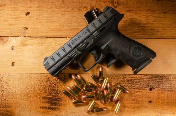 semi-automatic pistol with unspent ammo laying flat on a wooden background