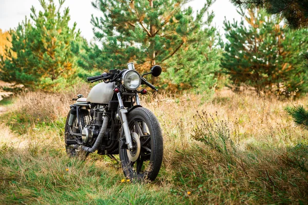 Silver vintage motorcycle parking on a country road. Everything is ready for having fun driving the empty road on a motorcycle tour journey. Modern hipster hobby. Space for your individual text.