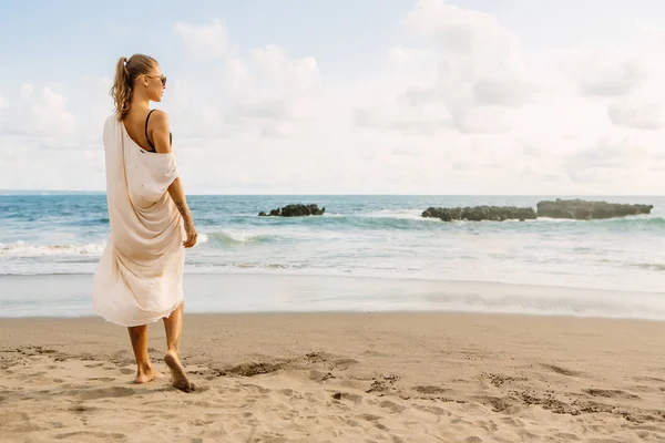 カジュアルな服と木製のサングラスのきれいな女性は 熱い砂の上宿泊です 海の熱帯ビーチ夕日や海の日の出の美しい女性 アクティブなヨガや瞑想ライフ スタイル コンセプト — ストック写真