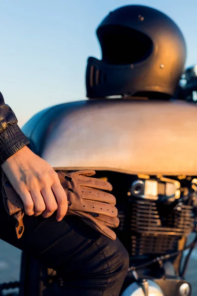 性感骑自行车的女人坐在老式定制 Caferacer 摩托车 黑色全脸头盔和皮革手套 城市屋顶停车场 日落在大城市 旅游和活跃的时髦生活方式 女孩力量 — 图库照片