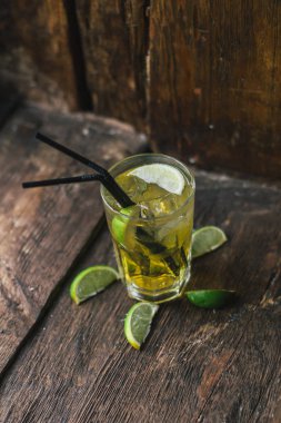 Lezzetli alkollü kokteyl limon ve kireç, ahşap arka plan üzerinde buz parçaları