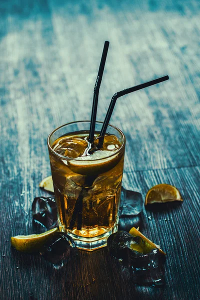 Lezzetli alkollü kokteyl limon ve kireç, ahşap arka plan üzerinde buz parçaları