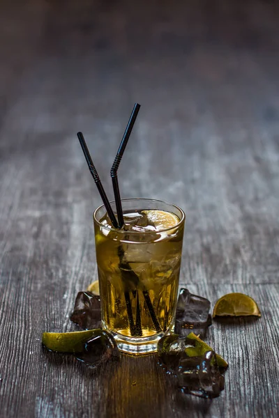 Lezzetli alkollü kokteyl limon ve kireç, ahşap arka plan üzerinde buz parçaları