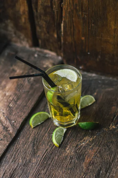 Lezzetli alkollü kokteyl limon ve kireç, ahşap arka plan üzerinde buz parçaları