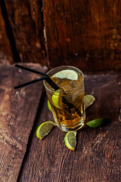 Lezzetli alkollü kokteyl limon ve kireç, ahşap arka plan üzerinde buz parçaları