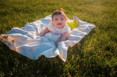 Çocuk çimlere bir altı aylık kız yatıyor.
