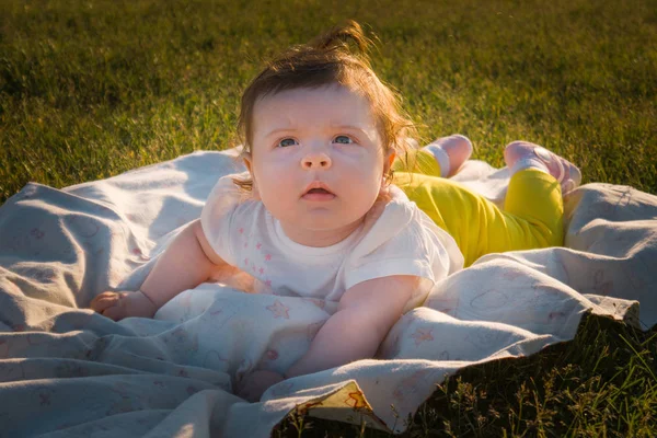 Çocuk çimlere bir altı aylık kız yatıyor.