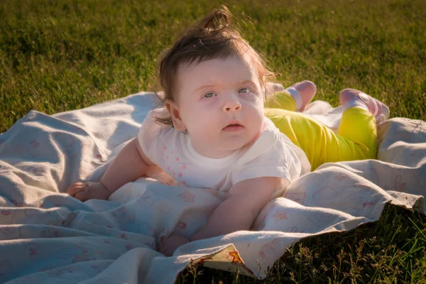 Çocuk çimlere bir altı aylık kız yatıyor.