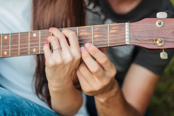 一个男人和一个女孩的手在吉他编曲 学会在公园的草坪上弹吉他 — 图库照片