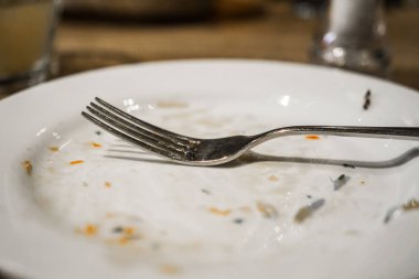 Bir plaka üzerinde bir yemekten sonra çatal. Masaya yiyecek izleri ile kirli tabak