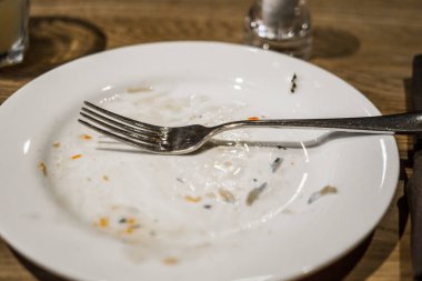 Bir plaka üzerinde bir yemekten sonra çatal. Masaya yiyecek izleri ile kirli tabak