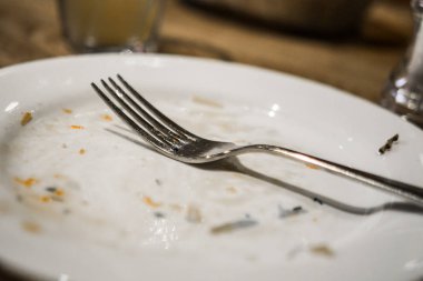 Bir plaka üzerinde bir yemekten sonra çatal. Masaya yiyecek izleri ile kirli tabak