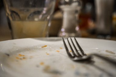 Bir plaka üzerinde bir yemekten sonra çatal. Masaya yiyecek izleri ile kirli tabak
