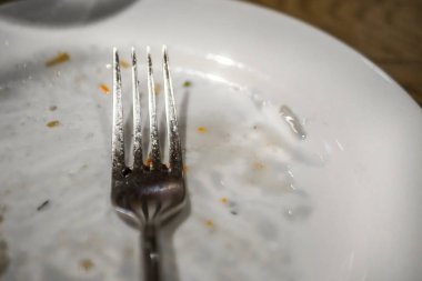 Bir plaka üzerinde bir yemekten sonra çatal. Masaya yiyecek izleri ile kirli tabak