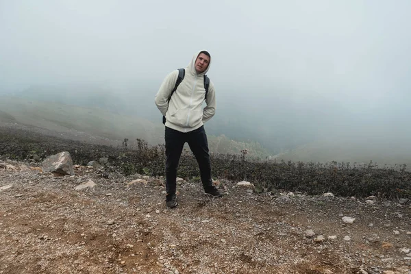 Divertido joven en las montañas tonteando, haciendo caras graciosas y poses . — Foto de Stock