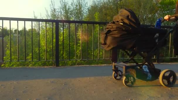 一个带着黑色婴儿车的女孩在城市中漫步 阳光明媚的一天 — 图库视频影像