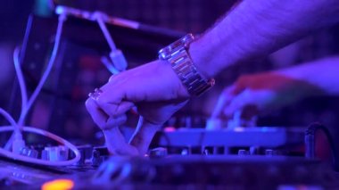 Bir gece kulübünde bir partide sahne alan bir Dj'in elleri. Neon ışıkları ve disko ışıkları