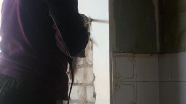 Builder yumruk tuğla eski sıva kaldırarak, eski duvarları kaldırır. dairede onarım