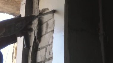 Builder yumruk tuğla eski sıva kaldırarak, eski duvarları kaldırır. dairede onarım