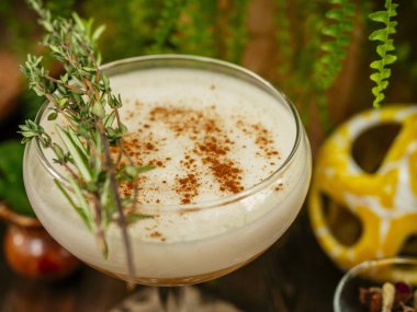 Uzun bacakta cam kadehte kahverengi kokteyl. Tropik bahçede. Düz bir taş üzerinde.