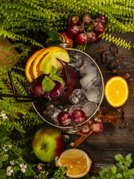 Red alcoholic cocktail in a bucket with ice. Garnished with fruits and berries on a wooden table. — Stock Photo, Image