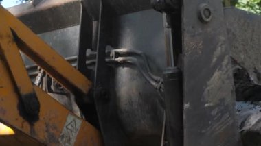 Bir traktör yeni asfalt döşemeden önce, bir konut binanın avlusında inşaat enkaz kaldırır. Güneşli yaz günü.