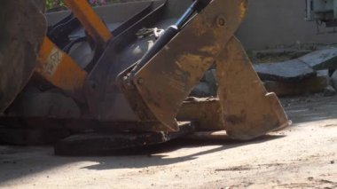 Bir traktör yeni asfalt döşemeden önce, bir konut binanın avlusında inşaat enkaz kaldırır. Güneşli yaz günü.