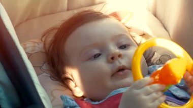 Bebek arabasında oyuncak olan bir çocuk oynuyor. Bir buçuk yıl kız. güneşli gün