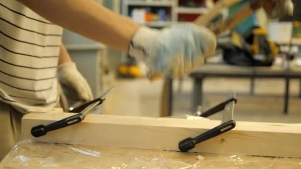 大工の工房の職人がクランプで固定されたボード上のゴムハンマーでノック — ストック動画