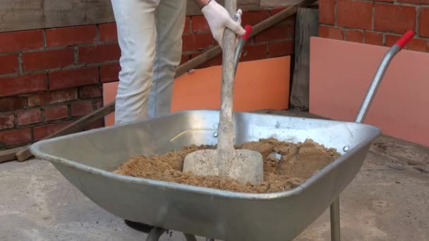 Een Man Schoppen Zand Van Een Kar Voor Een Betonmixer — Stockvideo