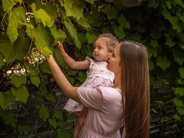 Mutter und Tochter spazieren und spielen im Park. gekleidet in Kleider. sonniger Tag, Wochenende im Stadtpark. — Stockfoto