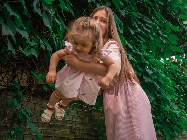 Mom and daughter walk and play in the park. Dressed in dresses. Sunny day, weekend in a city park. — Stock Photo, Image