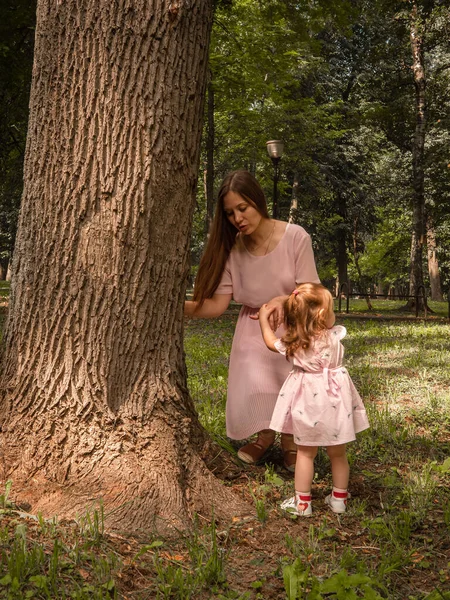 Mama i córka chodzą i bawią się w parku. Ubrana w sukienki. Słoneczny dzień, weekend w parku miejskim. — Zdjęcie stockowe