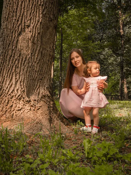 Mutter und Tochter spazieren und spielen im Park. gekleidet in Kleider. sonniger Tag, Wochenende im Stadtpark. — Stockfoto