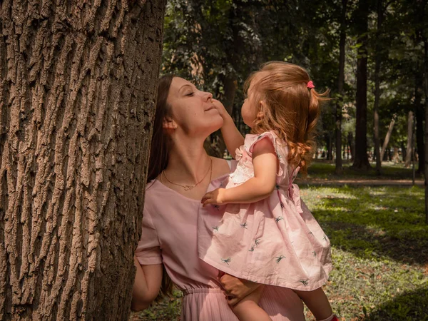 Mom and daughter walk and play in the park. Dressed in dresses. Sunny day, weekend in a city park. — Stock Photo, Image