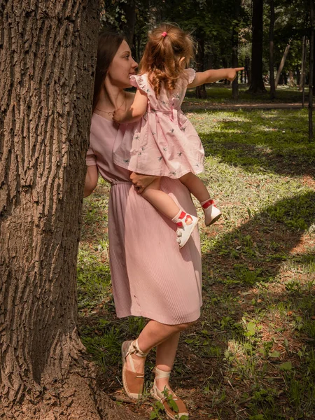 Мама і дочка ходять і граються в парку. Одягнені в сукні. Сонячний день, вихідні у міському парку.. — стокове фото