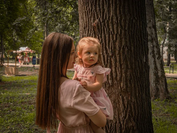 Mama i córka chodzą i bawią się w parku. Ubrana w sukienki. Słoneczny dzień, weekend w parku miejskim. — Zdjęcie stockowe