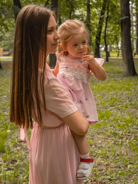 Мама и дочь гуляют и играют в парке. Одетые в платья. Солнечный день, выходные в городском парке . — стоковое фото