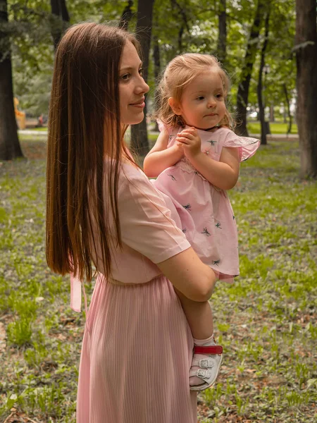 Mam en dochter lopen en spelen in het park. Gekleed in jurken. Zonnige dag, weekend in een stadspark. — Stockfoto