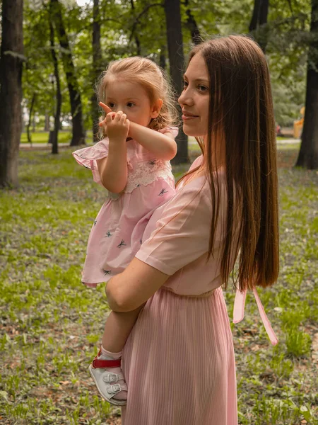 Mutter und Tochter spazieren und spielen im Park. gekleidet in Kleider. sonniger Tag, Wochenende im Stadtpark. — Stockfoto