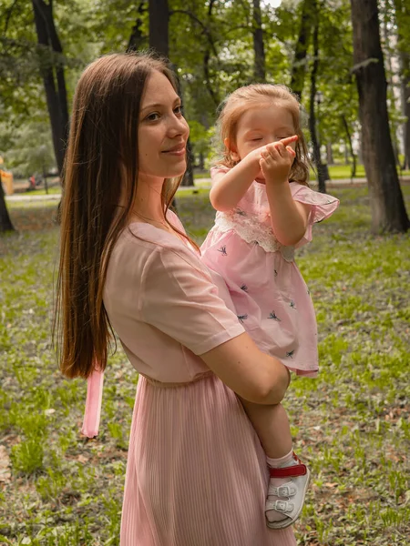 Mam en dochter lopen en spelen in het park. Gekleed in jurken. Zonnige dag, weekend in een stadspark. — Stockfoto