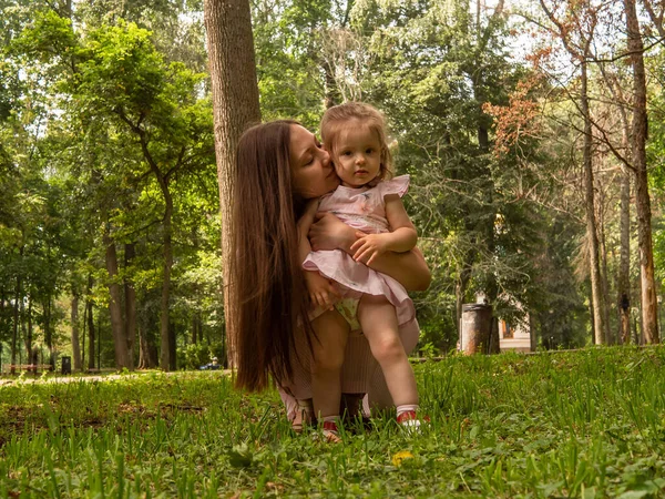 Mama i córka chodzą i bawią się w parku. Ubrana w sukienki. Słoneczny dzień, weekend w parku miejskim. — Zdjęcie stockowe