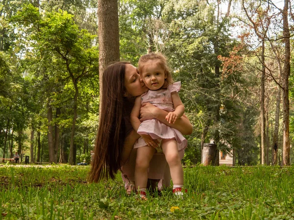 Mama i córka chodzą i bawią się w parku. Ubrana w sukienki. Słoneczny dzień, weekend w parku miejskim. — Zdjęcie stockowe