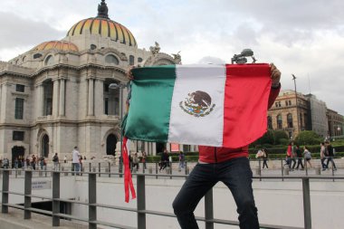 Mexico City, Mexico - 23 Ağustos 2023: Adam gururla CDMX şehir merkezindeki Palacio de Bellas Artes 'in önünde Meksika bayrağını kaldırdı.