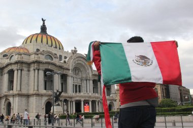 Mexico City, Mexico - 23 Ağustos 2023: Adam gururla CDMX şehir merkezindeki Palacio de Bellas Artes 'in önünde Meksika bayrağını kaldırdı.