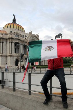 Mexico City, Mexico - 23 Ağustos 2023: Adam gururla CDMX şehir merkezindeki Palacio de Bellas Artes 'in önünde Meksika bayrağını kaldırdı.