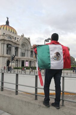 Mexico City, Mexico - 23 Ağustos 2023: Adam gururla CDMX şehir merkezindeki Palacio de Bellas Artes 'in önünde Meksika bayrağını kaldırdı.
